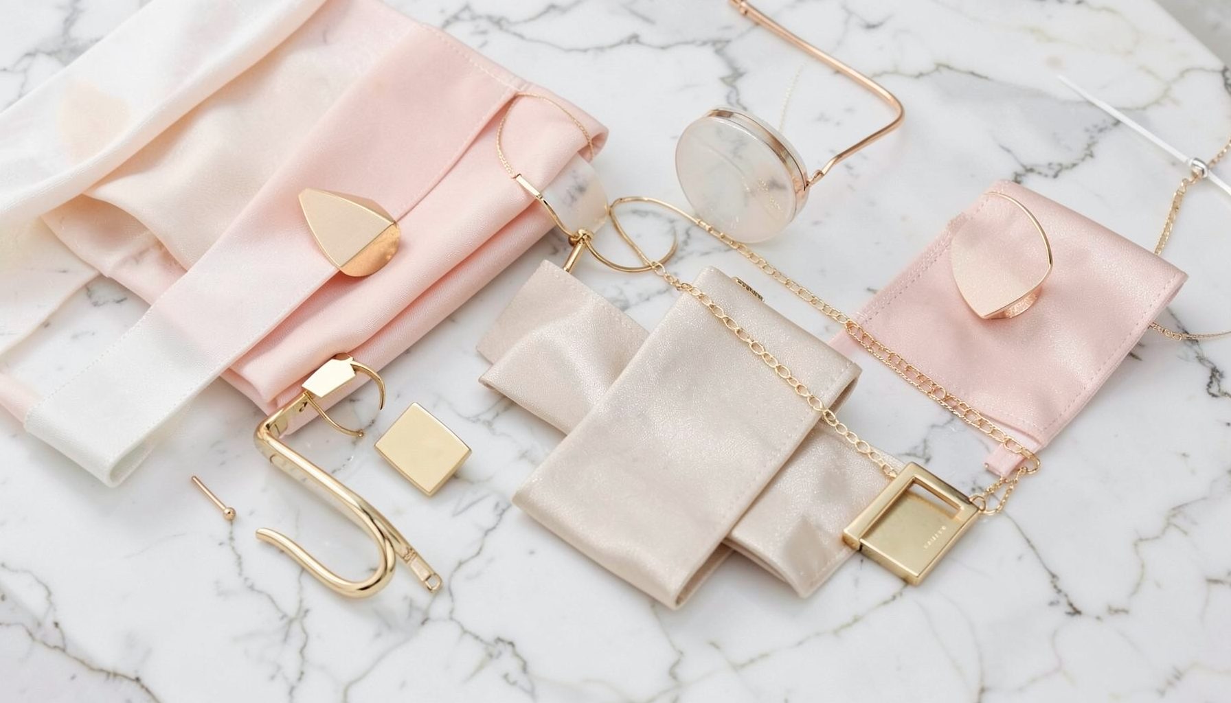 Fashion accessories arranged on a marble surface, elegant and refined in soft pastel and gold tones